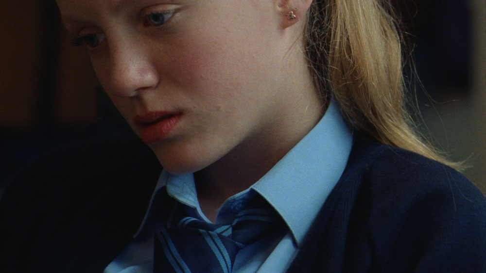 A young girl in a school uniform, looking sad.