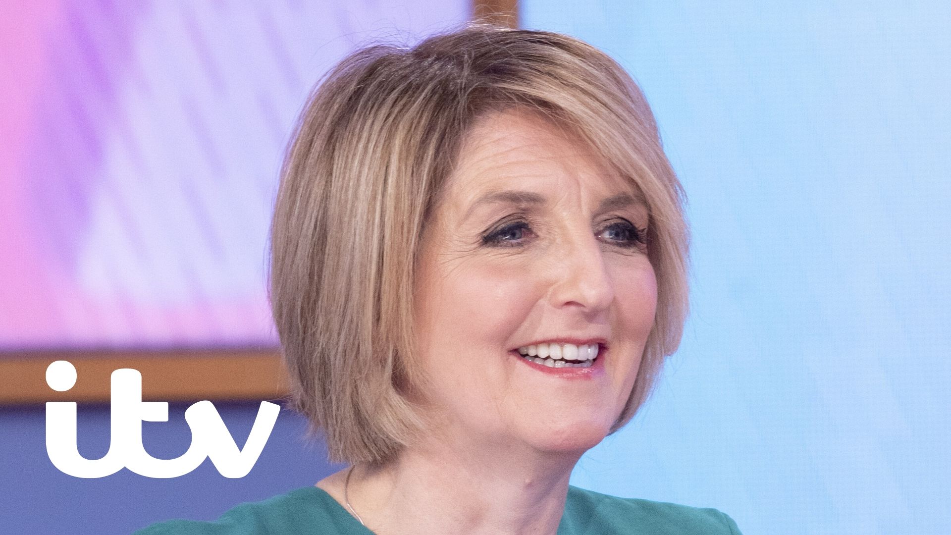 Presenter Kaye Adams smiles whilst looking off screen.